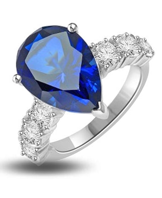 Diamond Essence Designer Ring with 5.50 cts. Pear Cut Sapphire Essence in center and three round stones on each side of center. 7.0 Cts. T. W. In Platinum Plated Sterling Silver.