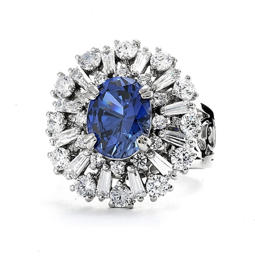 Diamond Essence Ring in Platinum Plated Sterling Silver with 2.5 carat Oval Sapphire Essence in the center, surrounded by Diamond Essence round stones and baguettes. Appx. 4.5 cts.t.w. on designer wide band. Just perfect for all occasions.