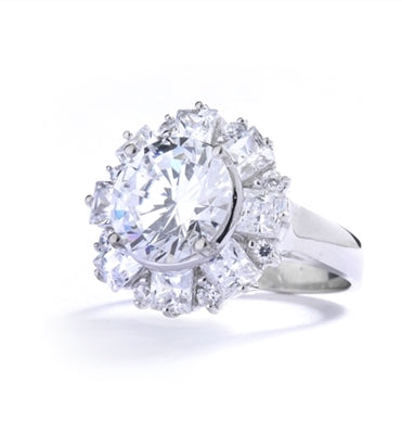 Diamond Essence Designer Ring With Round Brilliant Diamond Essence in center surrounded by alternately set Princess and melee. 7.25 Cts. T.W. set in Platinum Plated Sterling Silver.