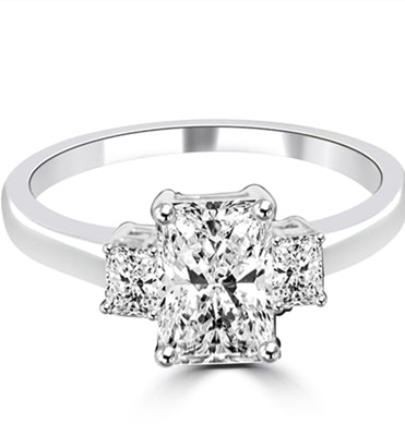 Brilliant Radiant Emerald Cut 3 Stone Ring With perfect balance Of 2.0 Cts. Brilliant Center and 0.5 Ct Sides. 3.0 Cts. T.W. set in Platinum Plated Sterling Silver.
