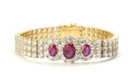 7" long Diamond Essence Bracelet with 2.0 Cts. Oval cut Ruby in center and 1.0 Ct. Ruby on each side encircled by Diamond Essence Stones making 3 rows all around wrist. Appx. 40.0 Cts. T.W. set in 14K Solid Yellow Gold.