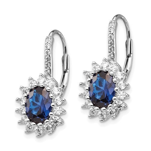 An alluring pair of prong set earrings for women with simulated oval cut sapphire in center surrounded by round brilliant melee Diamonds in floral pattern by Diamond Essence set in platinum plated sterling silver. 5.0 Cts.t.w.